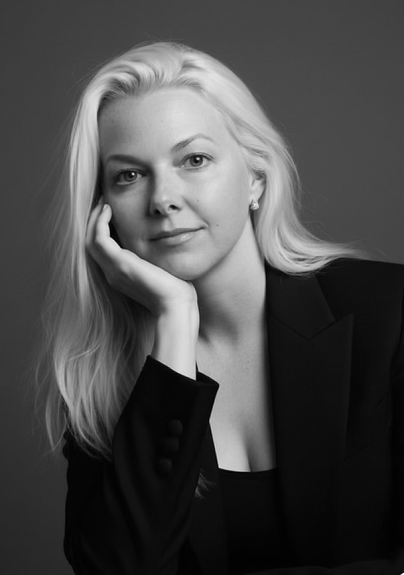 Black-and-white portrait of Tammy Kling in a dark blazer, resting her chin on her hand.